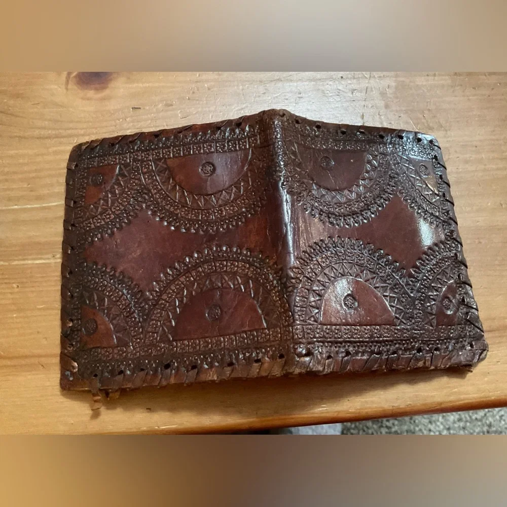 Hand crafted tooled mens leather design bifold wallet laced stitching around it.